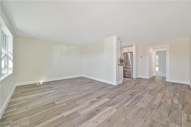 unfurnished living room featuring baseboards and light wood-style floors