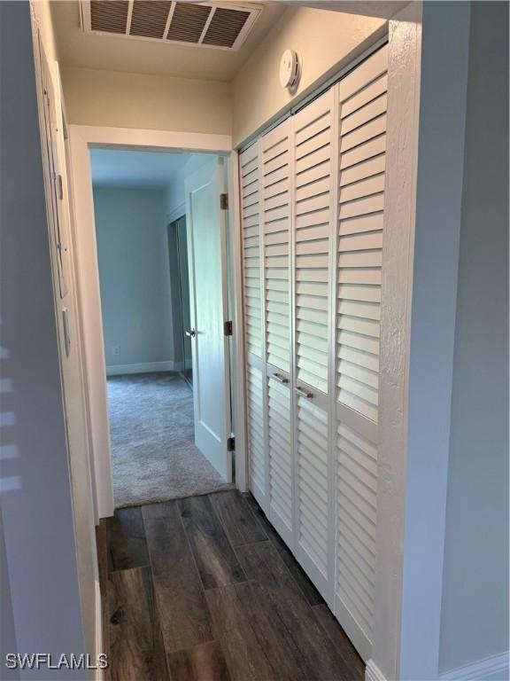 hall with dark wood-type flooring, baseboards, and visible vents