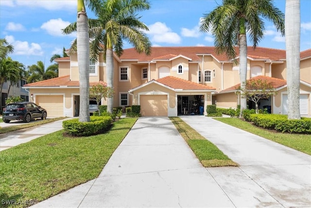 view of front of property featuring a front lawn, a tiled roof, stucco siding, a garage, and driveway