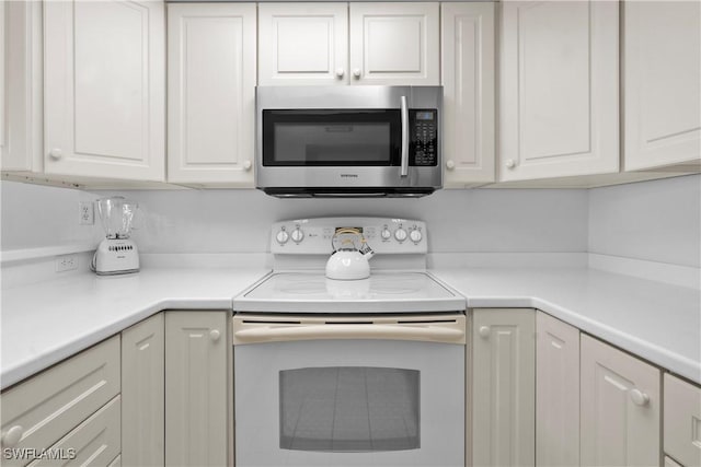 kitchen featuring white cabinetry, stainless steel microwave, light countertops, and white range with electric stovetop