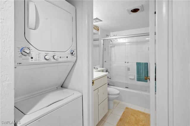 full bath with vanity, enclosed tub / shower combo, tile patterned flooring, stacked washer and clothes dryer, and toilet