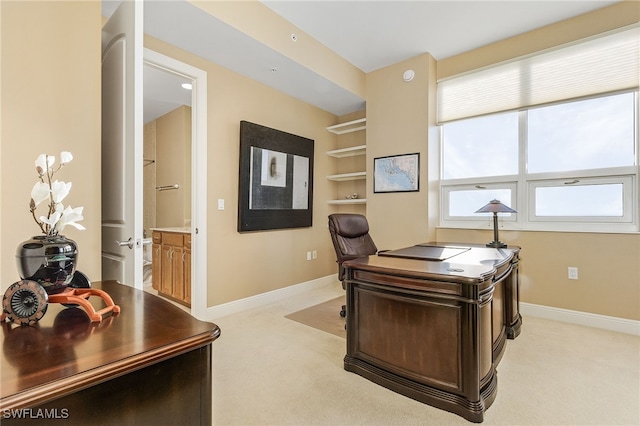 office area featuring baseboards and light carpet