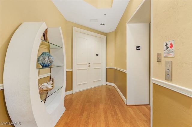 hall with baseboards and light wood-style floors