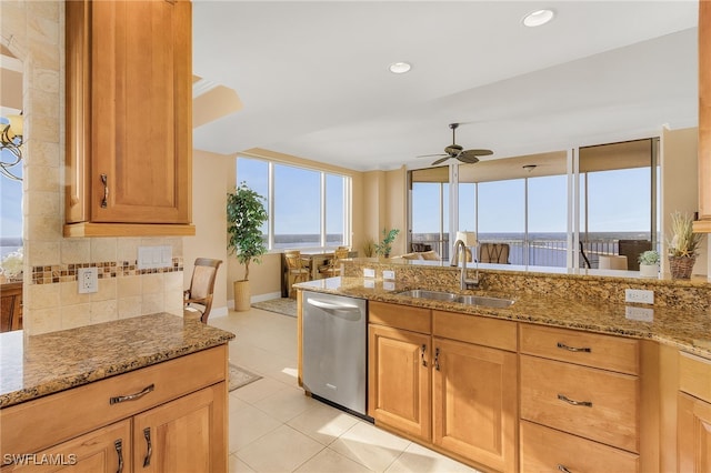 kitchen with tasteful backsplash, ceiling fan, light stone countertops, stainless steel dishwasher, and a sink