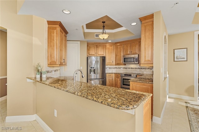 kitchen with a tray ceiling, appliances with stainless steel finishes, a peninsula, and decorative backsplash