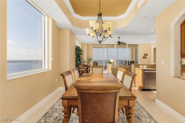 dining space featuring a tray ceiling, baseboards, a healthy amount of sunlight, and light tile patterned flooring