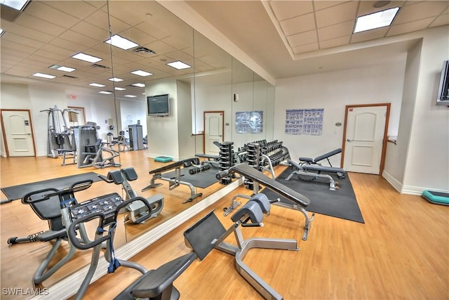 workout area with baseboards, wood finished floors, visible vents, and a paneled ceiling