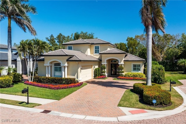 6849 Il Regalo Cir, Naples, FL 34109 - mediterranean / spanish-style house with decorative driveway, a tiled roof, an attached garage, and stucco siding