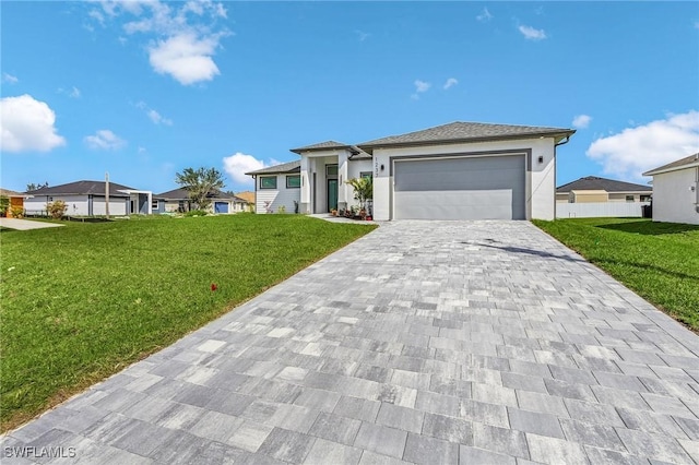 prairie-style home featuring stucco siding, an attached garage, decorative driveway, and a front lawn