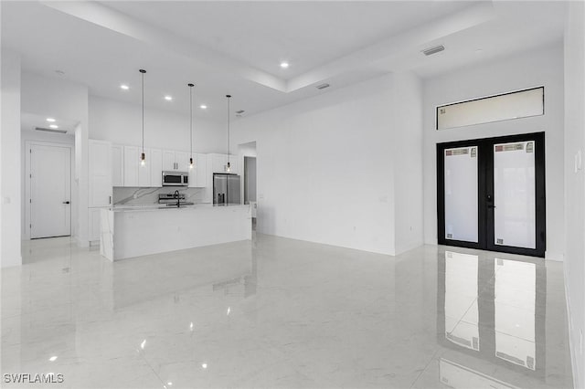 kitchen featuring marble finish floor, white cabinetry, french doors, a high ceiling, and appliances with stainless steel finishes