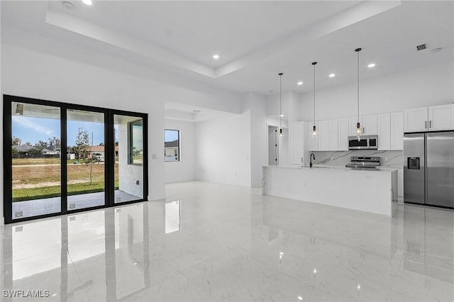 kitchen featuring marble finish floor, appliances with stainless steel finishes, a towering ceiling, and white cabinetry