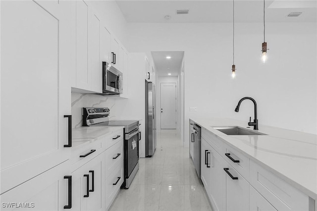 kitchen with white cabinets, light stone counters, appliances with stainless steel finishes, and a sink