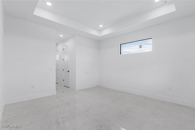 empty room featuring recessed lighting, baseboards, and a tray ceiling