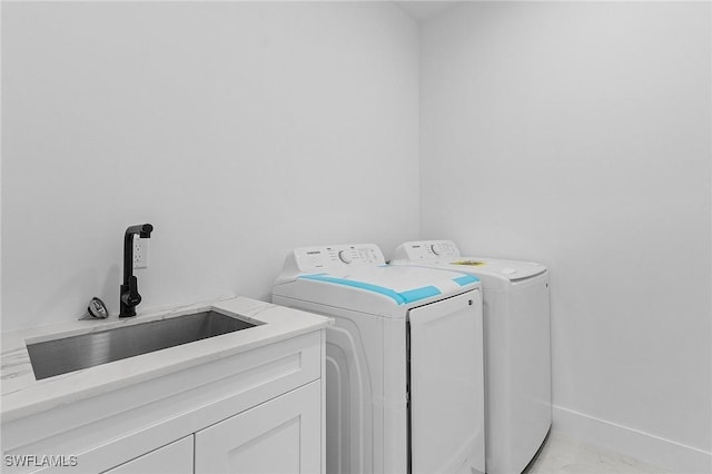 clothes washing area featuring baseboards, separate washer and dryer, cabinet space, marble finish floor, and a sink