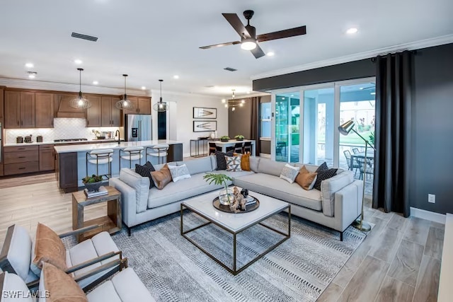 living area featuring visible vents, light wood-style flooring, ornamental molding, recessed lighting, and ceiling fan