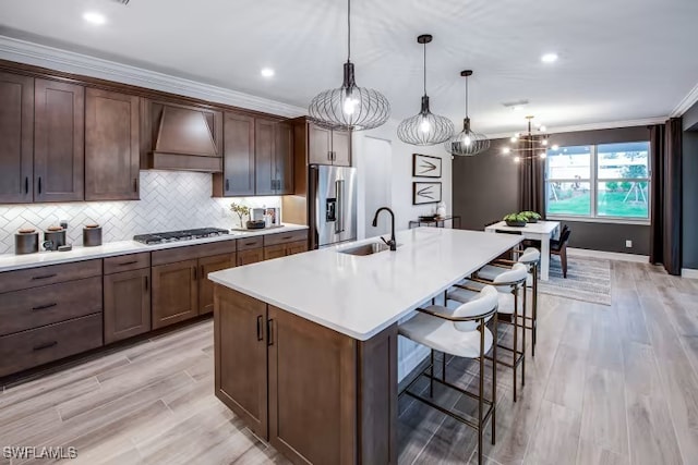 kitchen featuring a sink, crown molding, light countertops, custom exhaust hood, and high end refrigerator