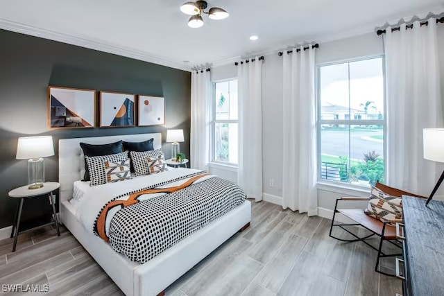 bedroom with crown molding, baseboards, and wood finish floors