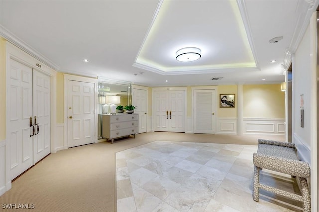 interior space with a decorative wall, a tray ceiling, and a wainscoted wall