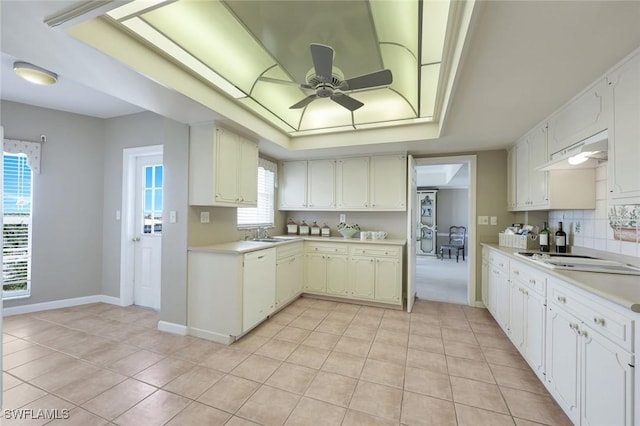 kitchen featuring white appliances, light tile patterned floors, a tray ceiling, ceiling fan, and light countertops