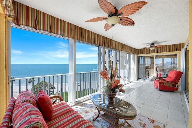 sunroom featuring a ceiling fan and a water view