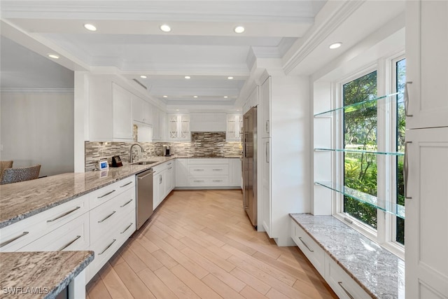 kitchen with light wood-style flooring, a sink, tasteful backsplash, appliances with stainless steel finishes, and white cabinets