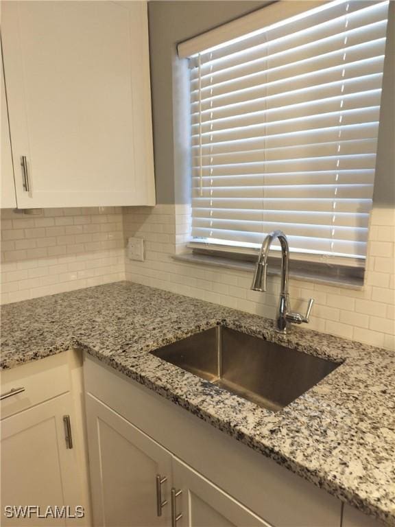 kitchen with white cabinets, a healthy amount of sunlight, tasteful backsplash, and a sink