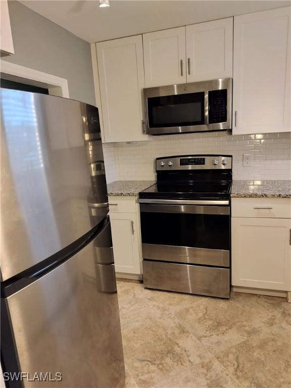 180 Turtle Lake Ct Unit 105, Naples, FL 34105 - kitchen featuring stainless steel appliances, white cabinetry, tasteful backsplash, and light stone countertops