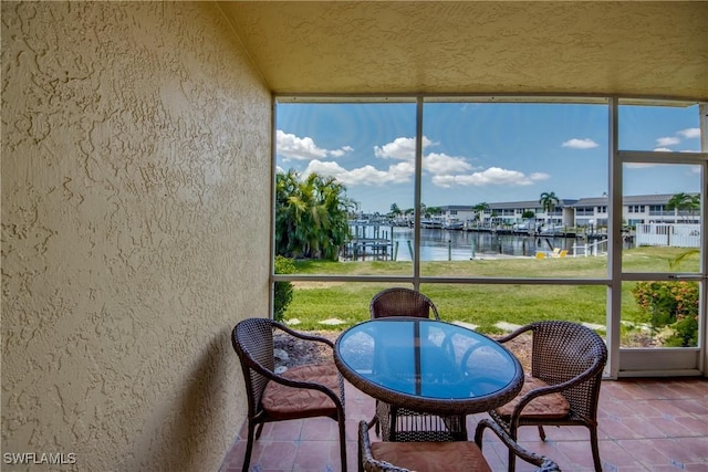 sunroom / solarium featuring plenty of natural light, lofted ceiling, and a water view