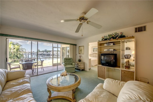 living area with visible vents, a ceiling fan, and carpet flooring