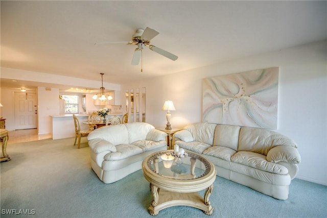 living area with ceiling fan with notable chandelier and light colored carpet