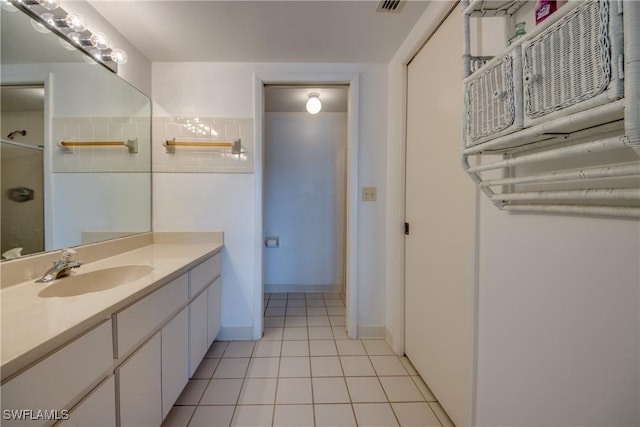 bathroom featuring tile patterned flooring, vanity, and a shower