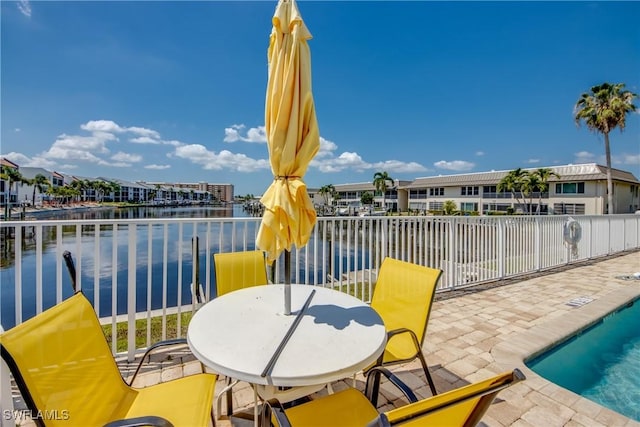 view of patio with fence, a community pool, and a water view