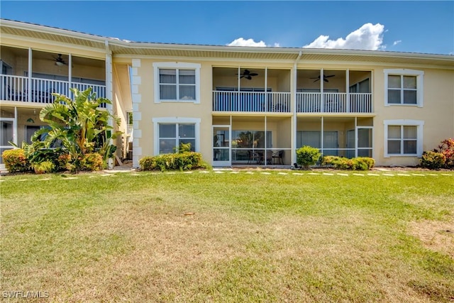 back of house featuring a balcony, a lawn, a ceiling fan, and stucco siding