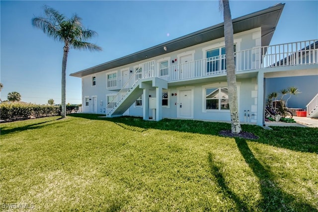 1950 Beach Pkwy Unit 103, Cape Coral, FL 33904 - rear view of house with stairs, a lawn, and stucco siding