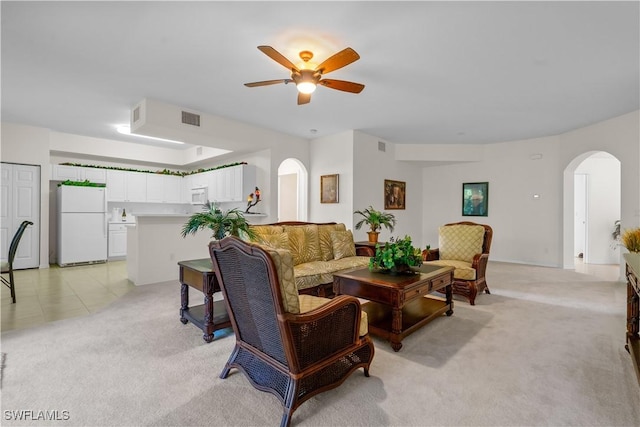 living room featuring a ceiling fan, visible vents, light colored carpet, and arched walkways