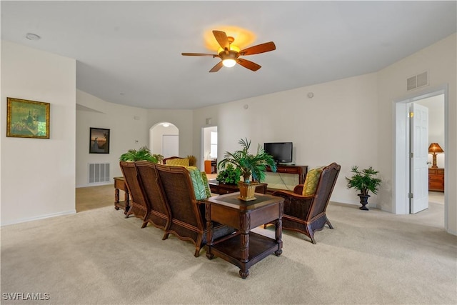 living area with light colored carpet, arched walkways, visible vents, and a ceiling fan