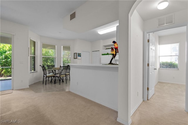 kitchen with visible vents, light carpet, arched walkways, and baseboards