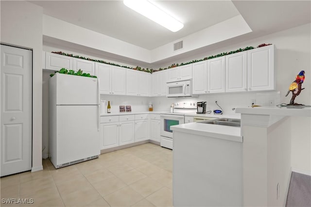 kitchen with visible vents, light countertops, a peninsula, white cabinets, and white appliances