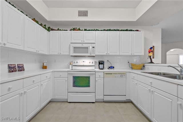 kitchen with visible vents, a sink, backsplash, white appliances, and light tile patterned floors