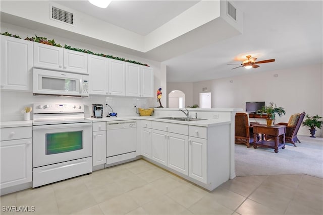 kitchen featuring visible vents, a sink, white appliances, a peninsula, and light countertops