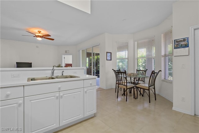 kitchen featuring light tile patterned flooring, ceiling fan, a sink, light countertops, and white cabinetry