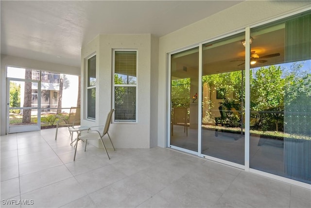 unfurnished sunroom featuring a ceiling fan