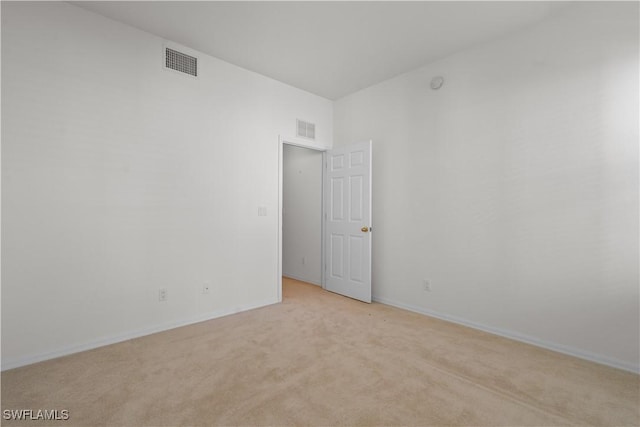 spare room with light colored carpet, visible vents, and baseboards