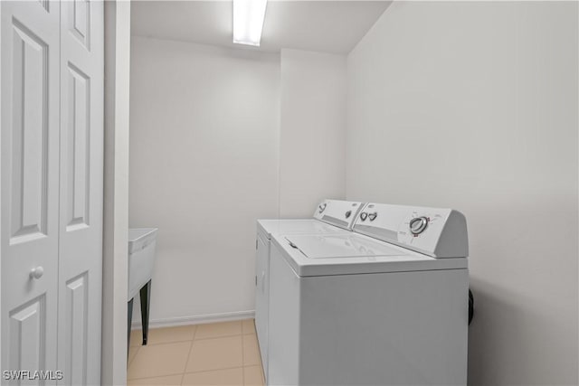 clothes washing area with washer and clothes dryer, laundry area, baseboards, and light tile patterned floors