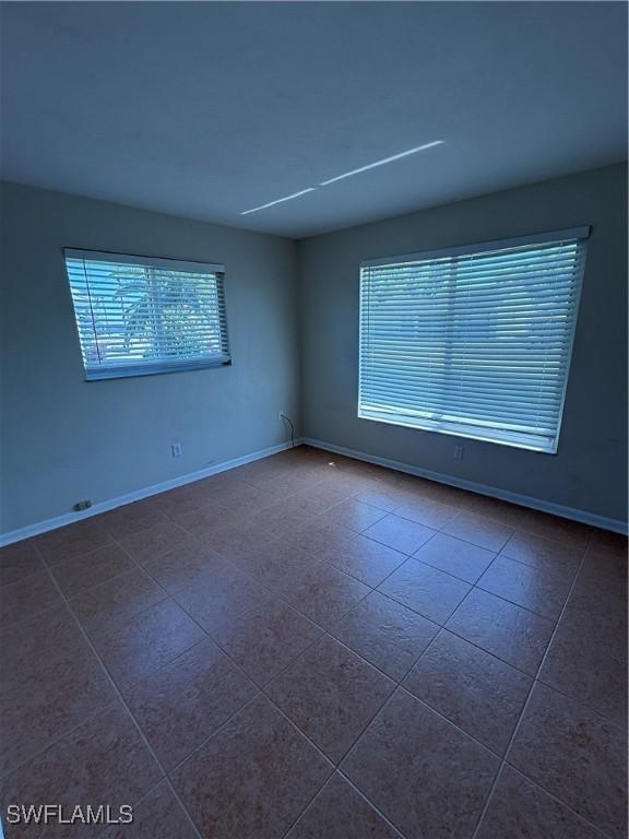 empty room with dark tile patterned floors and baseboards