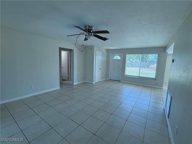 unfurnished living room with light tile patterned floors, visible vents, baseboards, and a ceiling fan