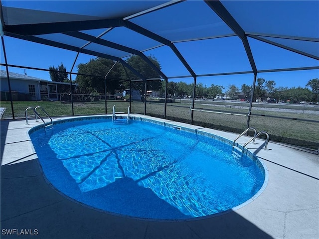 outdoor pool with glass enclosure, a patio, and a lawn