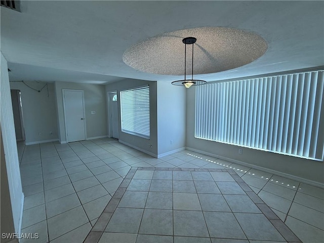 tiled spare room featuring visible vents, baseboards, and a textured ceiling