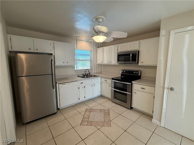 kitchen with light tile patterned flooring, a sink, light countertops, white cabinets, and appliances with stainless steel finishes