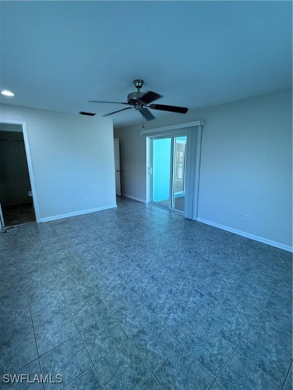 spare room with a ceiling fan and baseboards